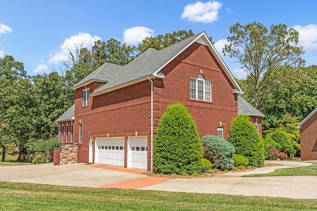 view of side of property featuring a yard, concrete driveway, brick siding, and an attached garage