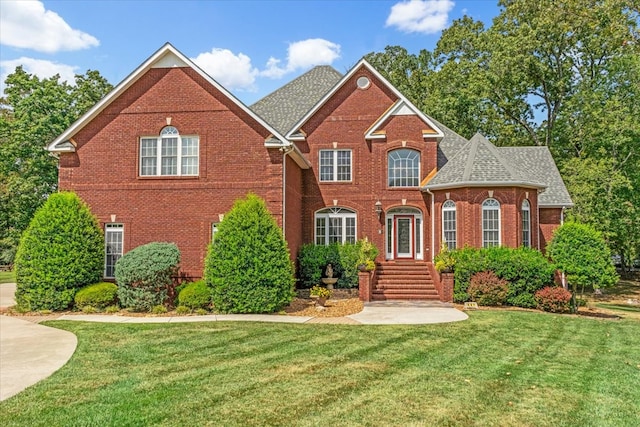 traditional-style home featuring brick siding, roof with shingles, and a front yard