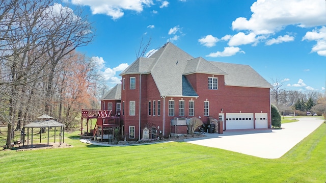 view of side of property featuring a garage, a gazebo, a yard, and brick siding