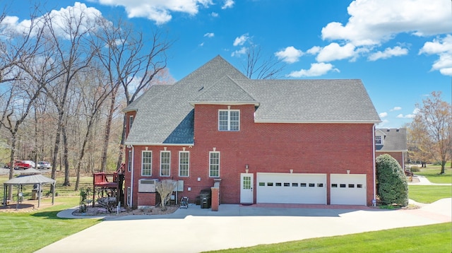 view of side of home featuring a shingled roof, an attached garage, a gazebo, a yard, and brick siding