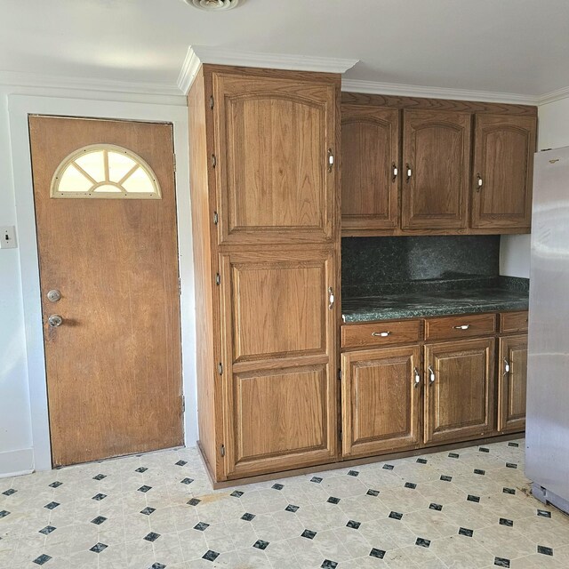 kitchen featuring light tile patterned floors, tasteful backsplash, crown molding, and fridge