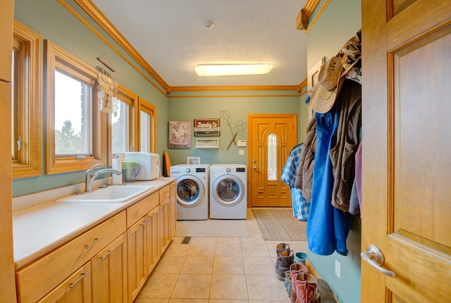 washroom featuring light tile patterned flooring, sink, ornamental molding, cabinets, and washer and dryer