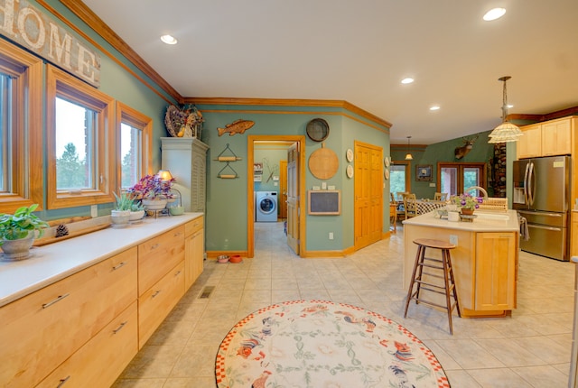 kitchen featuring light brown cabinets, washer / dryer, light tile patterned floors, stainless steel fridge with ice dispenser, and a center island