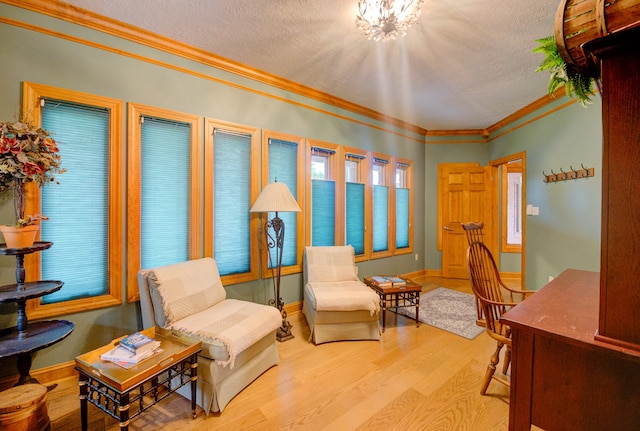 living area with a textured ceiling, crown molding, an inviting chandelier, and hardwood / wood-style flooring