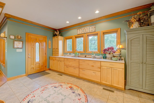 kitchen with light tile patterned floors, ornamental molding, and light brown cabinetry