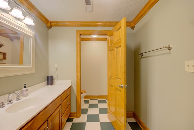 bathroom with toilet, crown molding, vanity, and tile patterned floors