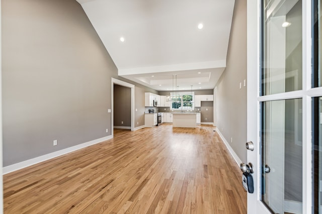 unfurnished living room featuring a tray ceiling and light hardwood / wood-style flooring