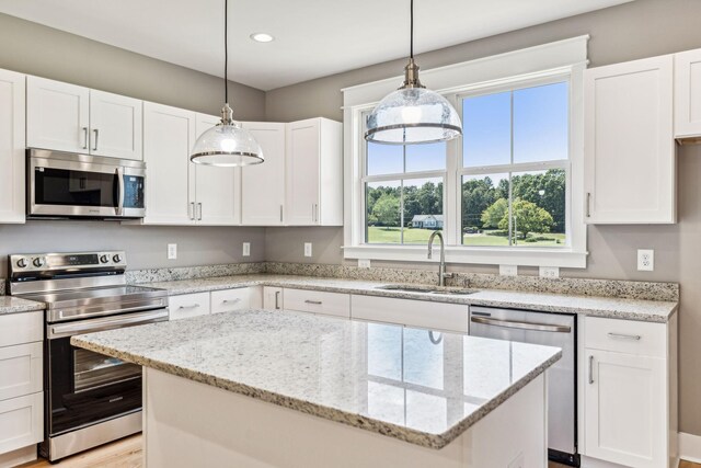 kitchen featuring pendant lighting, stainless steel appliances, white cabinetry, and sink