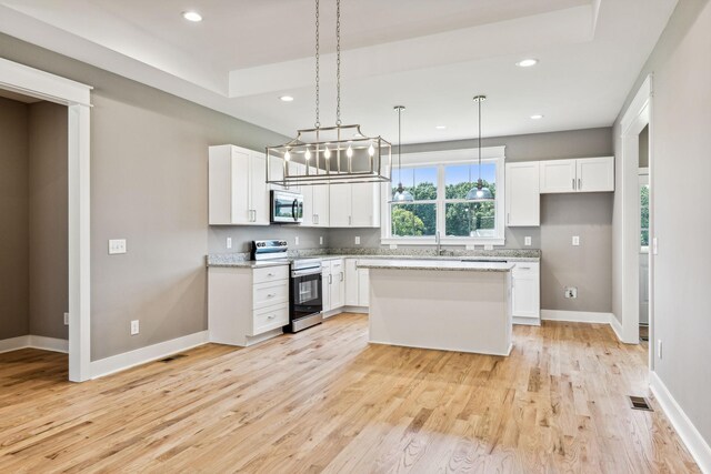 kitchen with light stone countertops, a center island, stainless steel appliances, light hardwood / wood-style floors, and white cabinets