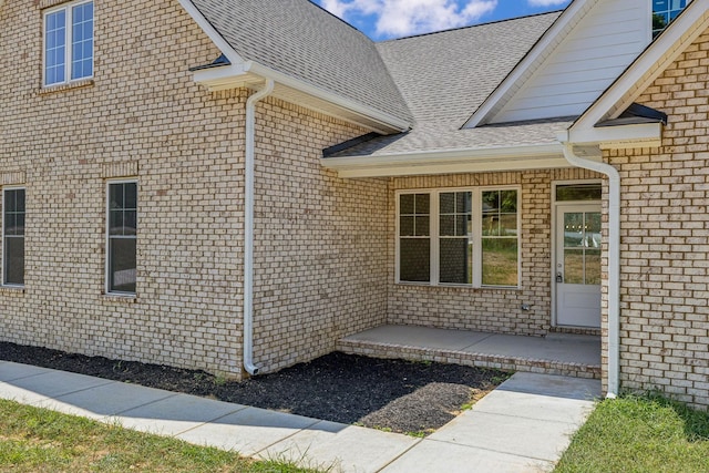 view of side of home with brick siding and roof with shingles