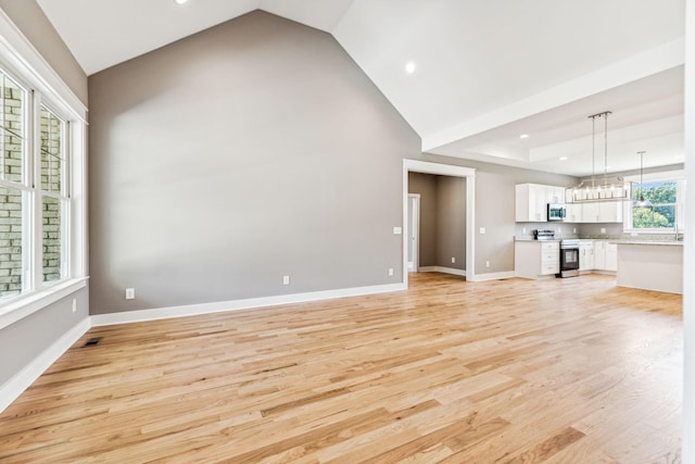 unfurnished living room with a chandelier, light wood finished floors, recessed lighting, and baseboards