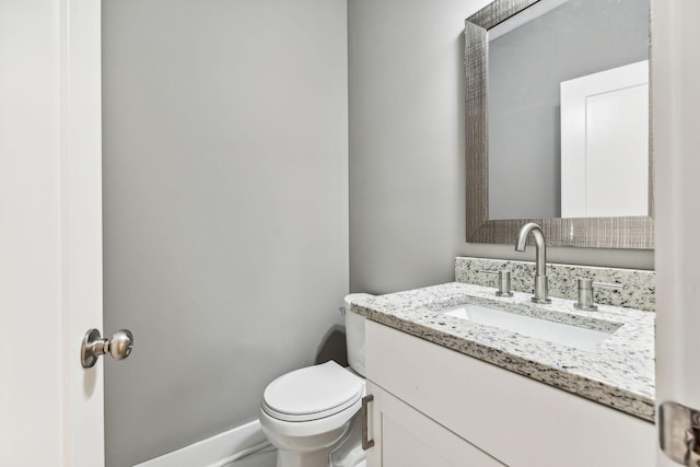 bathroom featuring toilet, baseboards, and vanity