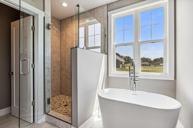 full bathroom with baseboards, a soaking tub, marble finish floor, a shower stall, and a sink