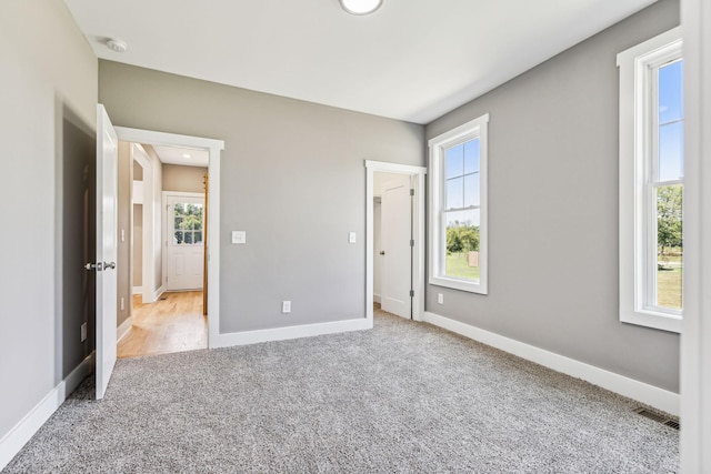 unfurnished bedroom with multiple windows, baseboards, and carpet flooring