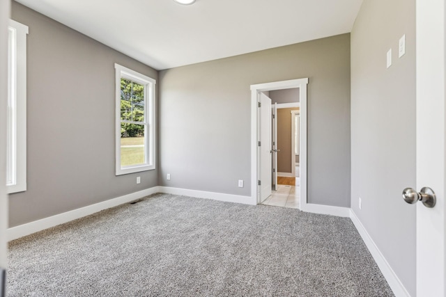 empty room featuring light carpet, visible vents, and baseboards