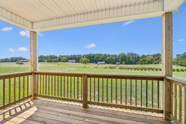 wooden terrace featuring a yard and a rural view