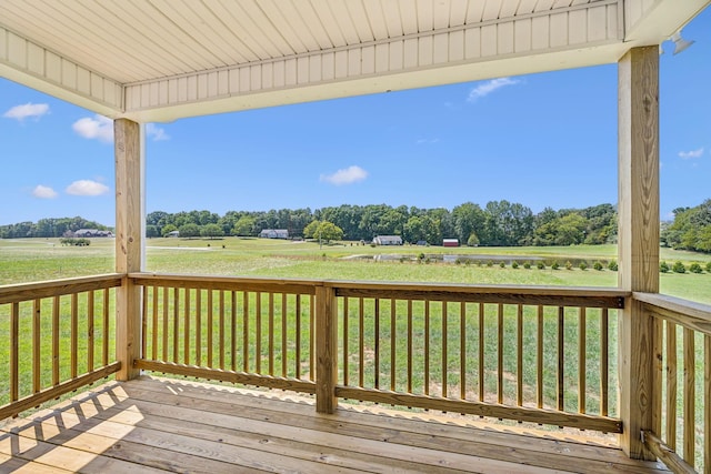 wooden terrace with a rural view and a lawn