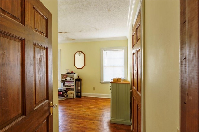 corridor with a textured ceiling, crown molding, and dark hardwood / wood-style flooring