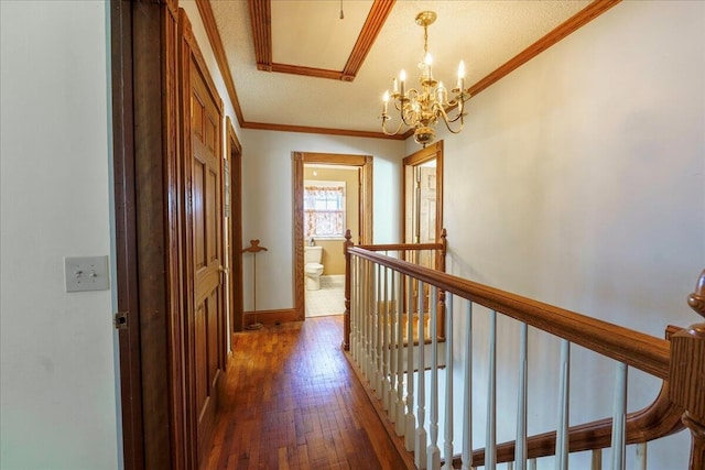 corridor with a textured ceiling, ornamental molding, hardwood / wood-style floors, and an inviting chandelier