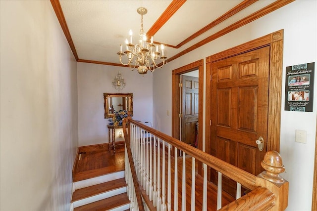 staircase with ornamental molding, hardwood / wood-style floors, and an inviting chandelier