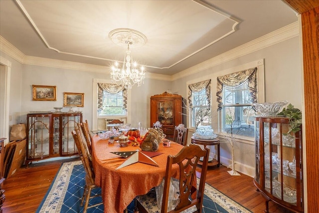 dining room with hardwood / wood-style floors, crown molding, and an inviting chandelier