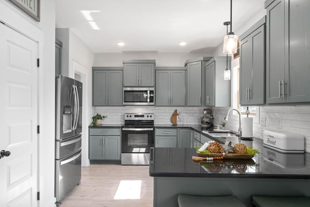 kitchen featuring appliances with stainless steel finishes, sink, pendant lighting, gray cabinets, and decorative backsplash