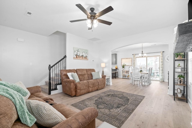 living room with ceiling fan with notable chandelier and light hardwood / wood-style flooring