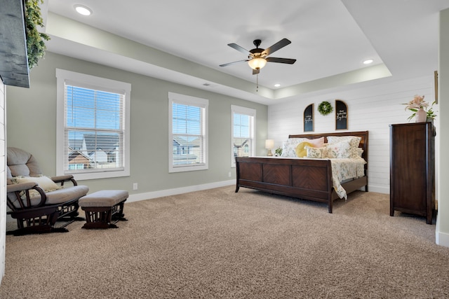 carpeted bedroom featuring a tray ceiling and ceiling fan