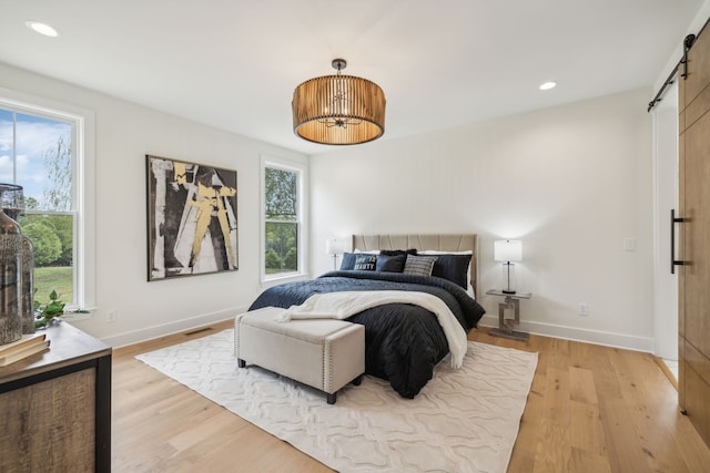 bedroom featuring a barn door and light wood-type flooring