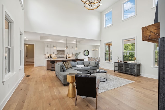 living room featuring light hardwood / wood-style flooring, an inviting chandelier, and a high ceiling