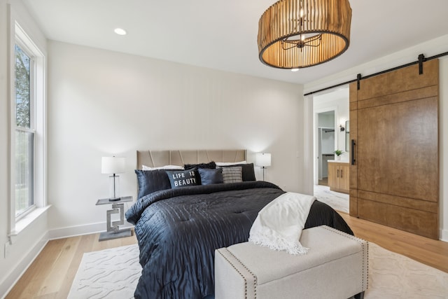 bedroom featuring a barn door, multiple windows, and light hardwood / wood-style flooring