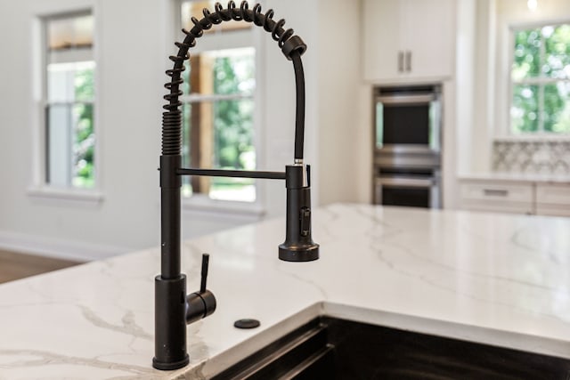 interior details featuring double oven and light stone countertops