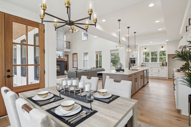 dining area featuring a towering ceiling, plenty of natural light, light hardwood / wood-style flooring, and sink