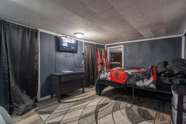 bedroom with wood-type flooring and wooden walls