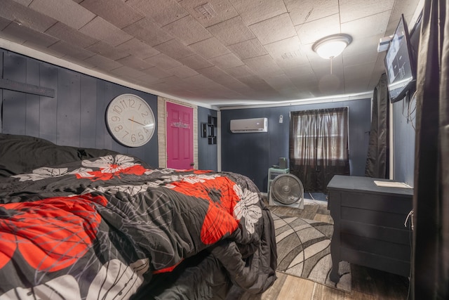 bedroom with a wall unit AC and wood-type flooring