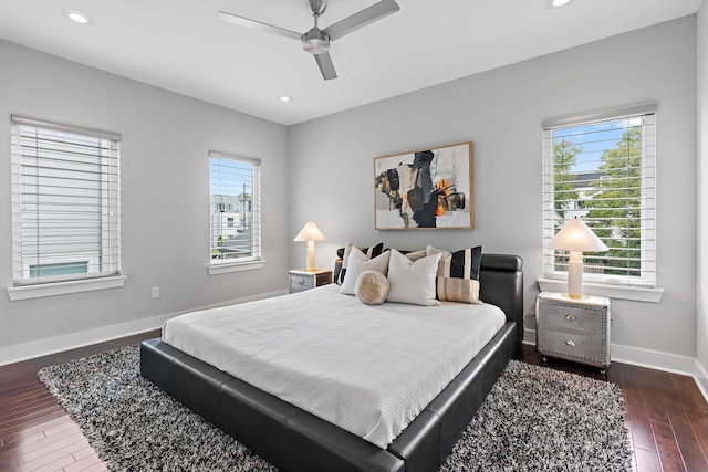 bedroom with ceiling fan, dark wood-type flooring, and multiple windows