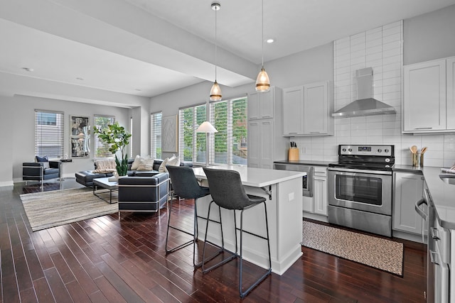 kitchen with wall chimney exhaust hood, tasteful backsplash, stainless steel electric range, white cabinets, and dark wood-type flooring