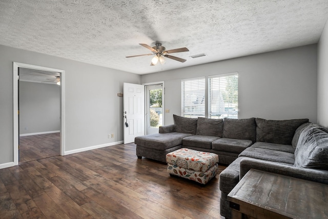 living room with ceiling fan, dark hardwood / wood-style floors, and a textured ceiling