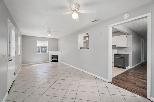 unfurnished living room with ceiling fan, beverage cooler, and light tile patterned floors