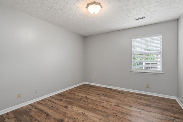 spare room featuring a textured ceiling and hardwood / wood-style floors