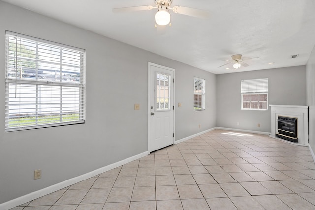 unfurnished living room featuring plenty of natural light, ceiling fan, and light tile patterned flooring