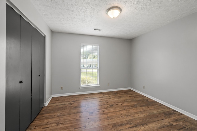 unfurnished bedroom with a textured ceiling, a closet, and wood-type flooring