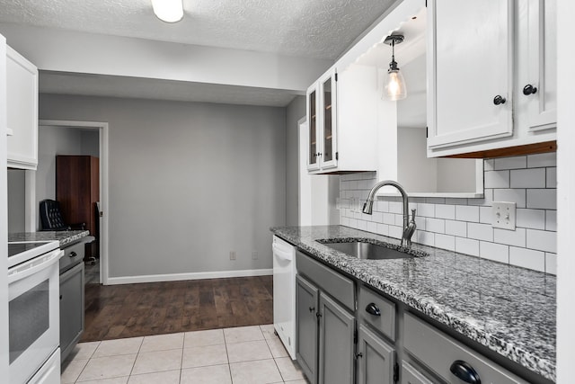 kitchen with decorative backsplash, pendant lighting, range, sink, and light tile patterned flooring