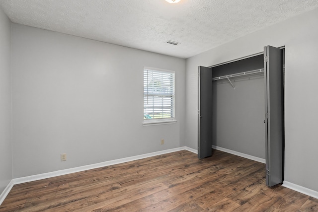 unfurnished bedroom featuring a textured ceiling, a closet, and hardwood / wood-style flooring