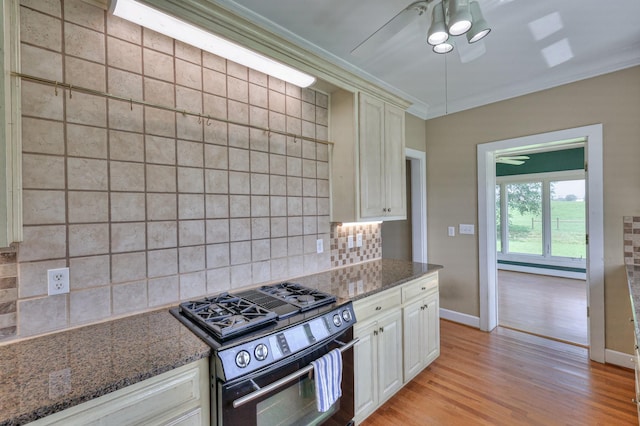 kitchen with light hardwood / wood-style floors, gas stove, backsplash, ornamental molding, and dark stone countertops