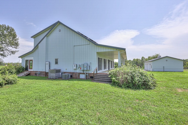 back of house featuring central air condition unit and a yard