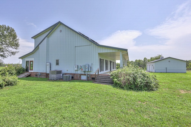 back of property featuring cooling unit and a lawn