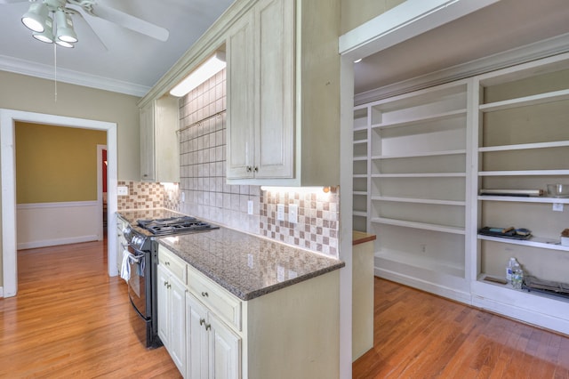 kitchen featuring light hardwood / wood-style flooring, tasteful backsplash, range with gas stovetop, white cabinets, and ceiling fan