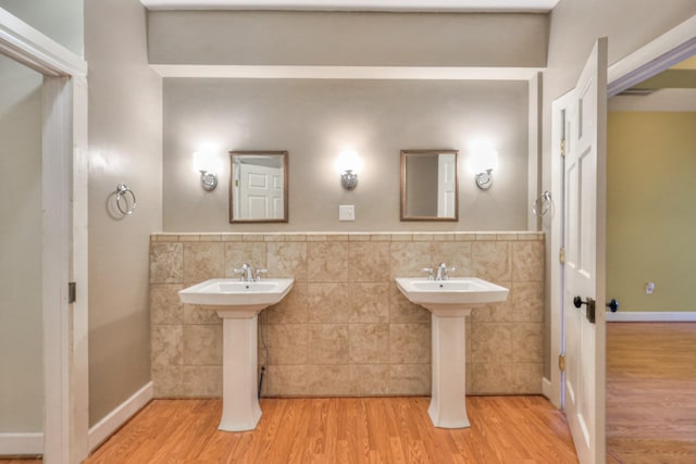 bathroom with tile walls, wood-type flooring, and dual sinks
