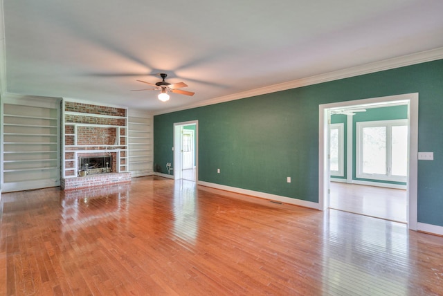 unfurnished living room featuring ornamental molding, light hardwood / wood-style floors, a brick fireplace, and built in features